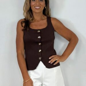 Vrouw draagt een By Clara gilet in bruin met gouden details.