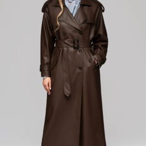 Vrouw draagt een lange bruine Attentif Paris trenchcoat met ceintuur en luxe knopen.