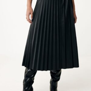 zwarte imitatieleer plissé rok midi model gecombineerd met hoge zwarte laarzen en een witte top.